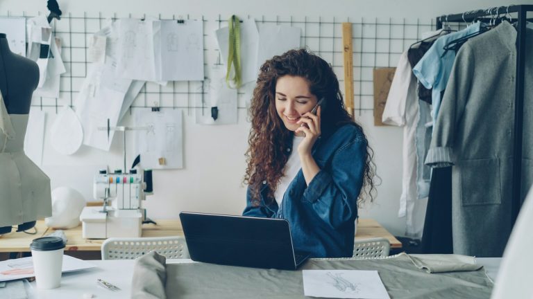 Small business owner using a laptop and phone to manage AI automation for small business tasks